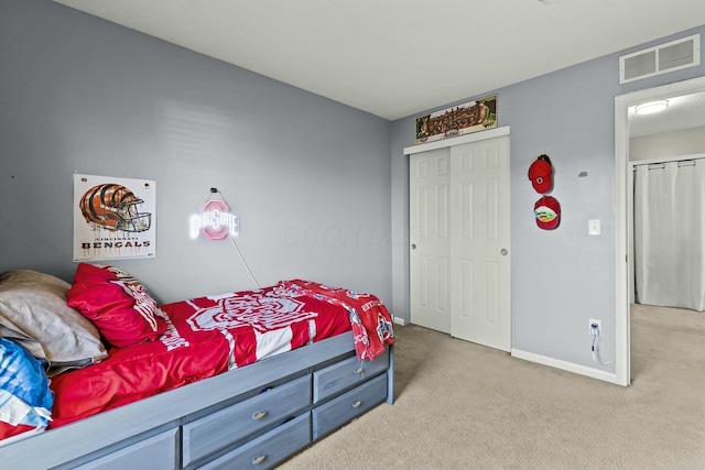 bedroom with light colored carpet, a closet, visible vents, and baseboards