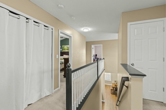 hallway featuring visible vents, baseboards, an upstairs landing, and light colored carpet