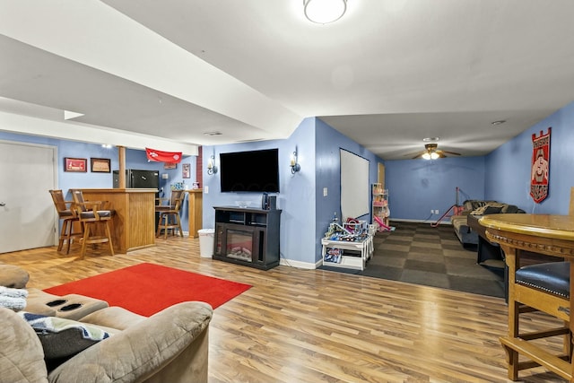 living room featuring a dry bar, baseboards, ceiling fan, wood finished floors, and a fireplace