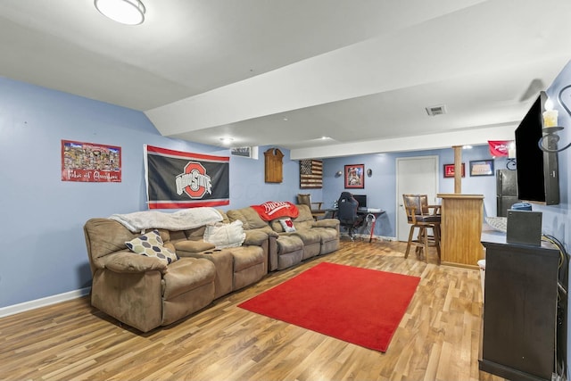 living room with lofted ceiling, light wood-style flooring, visible vents, and baseboards