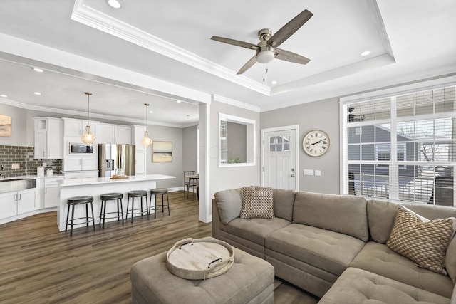 living area featuring recessed lighting, a ceiling fan, a tray ceiling, dark wood finished floors, and crown molding