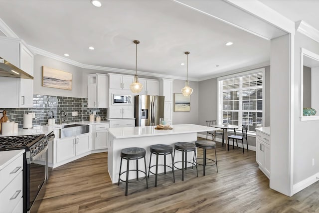 kitchen with appliances with stainless steel finishes, light countertops, a kitchen island, and white cabinetry