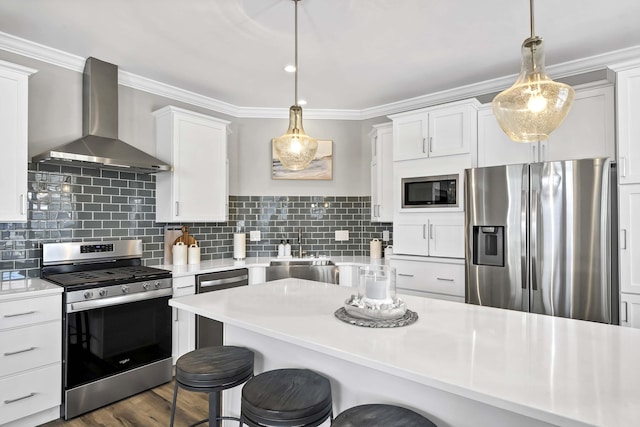 kitchen featuring light countertops, appliances with stainless steel finishes, wall chimney range hood, and white cabinets