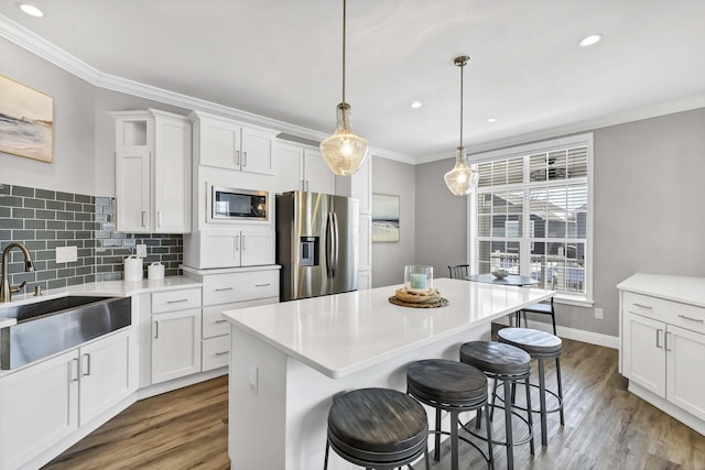 kitchen with stainless steel fridge, white cabinetry, light countertops, and a sink