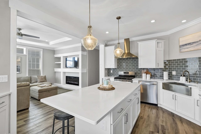 kitchen featuring a center island, light countertops, appliances with stainless steel finishes, white cabinetry, and wall chimney exhaust hood