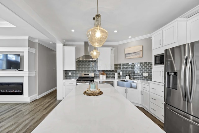 kitchen featuring stainless steel appliances, a sink, white cabinetry, light countertops, and wall chimney exhaust hood