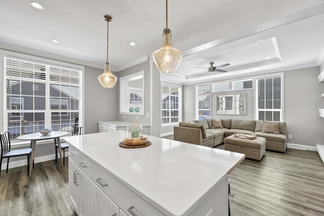 kitchen featuring crown molding, light countertops, hanging light fixtures, white cabinets, and a kitchen island