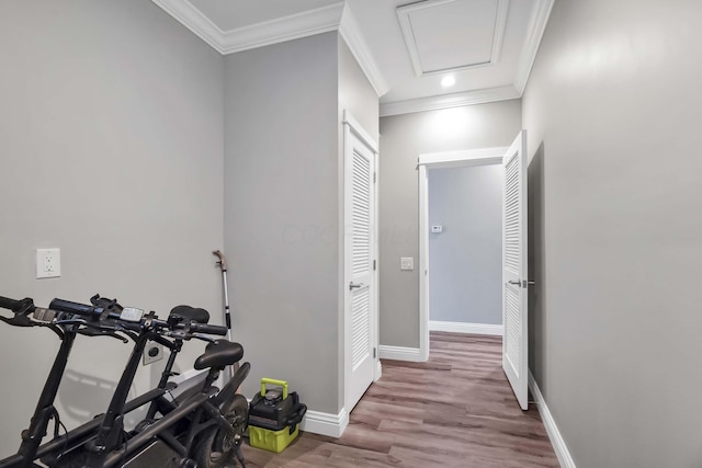 exercise area with ornamental molding, light wood-type flooring, attic access, and baseboards