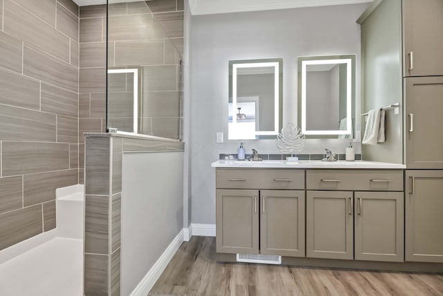 bathroom featuring wood finished floors, walk in shower, a sink, and double vanity