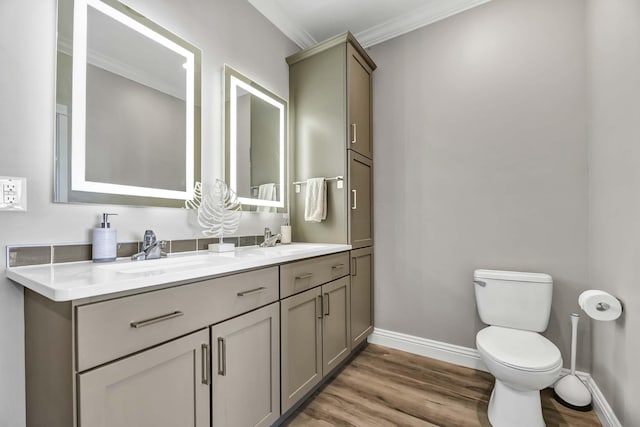 full bath with baseboards, toilet, wood finished floors, crown molding, and a sink