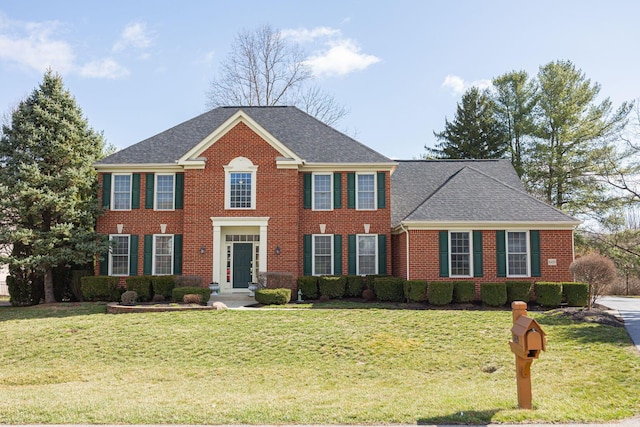 colonial-style house featuring brick siding, a front lawn, and roof with shingles