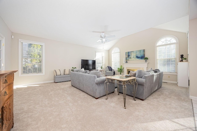 living area with light carpet, a healthy amount of sunlight, a ceiling fan, and vaulted ceiling