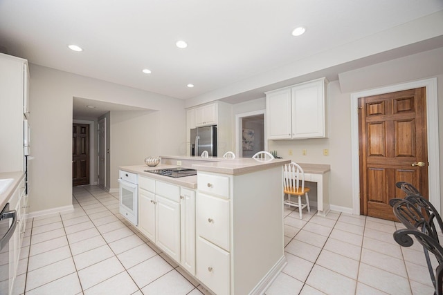 kitchen featuring a center island, light countertops, stainless steel refrigerator with ice dispenser, light tile patterned flooring, and white oven