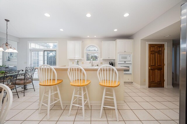 kitchen featuring light tile patterned flooring, white appliances, and a breakfast bar