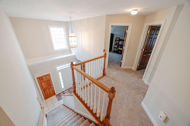 stairway featuring a textured ceiling, baseboards, and carpet