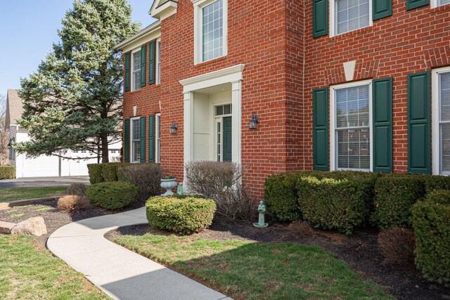 view of exterior entry with brick siding, driveway, and a garage