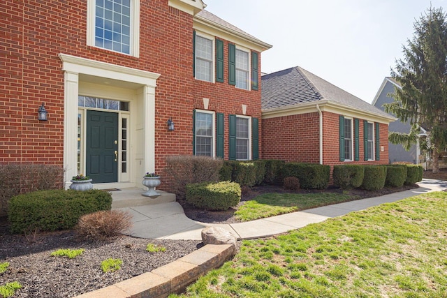 entrance to property with brick siding and roof with shingles