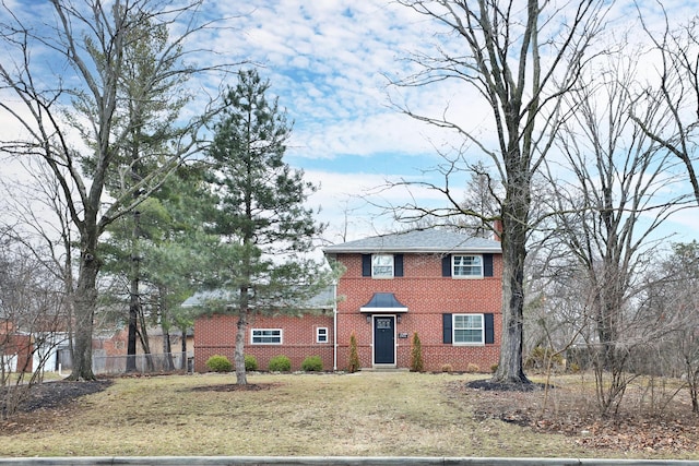 colonial inspired home with fence, a front lawn, and brick siding