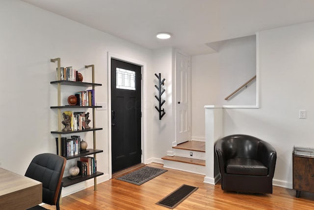 foyer entrance with baseboards, visible vents, and wood finished floors