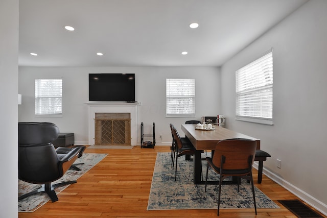 dining space with light wood-type flooring, a high end fireplace, visible vents, and recessed lighting