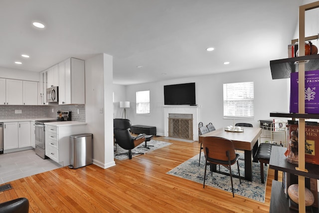 interior space with appliances with stainless steel finishes, light countertops, light wood-style flooring, and tasteful backsplash