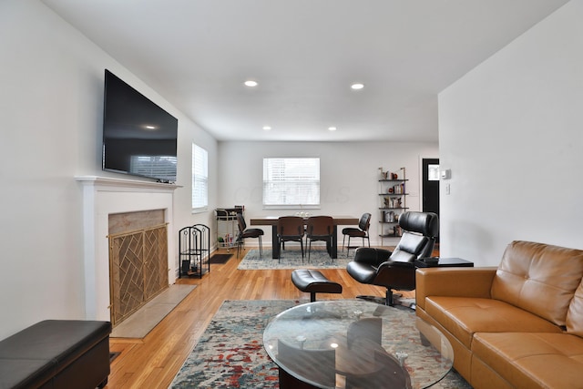 living area featuring light wood-style floors, a premium fireplace, baseboards, and recessed lighting