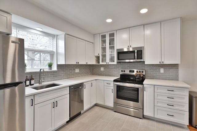 kitchen featuring stainless steel appliances, light countertops, a sink, and backsplash