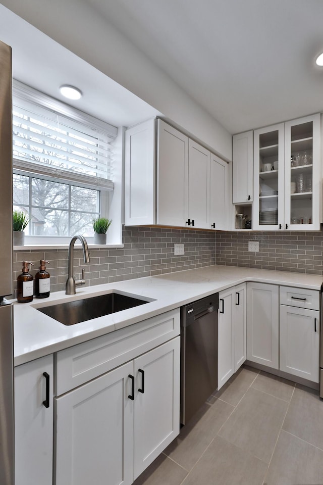 kitchen featuring dishwasher, light countertops, tasteful backsplash, and a sink