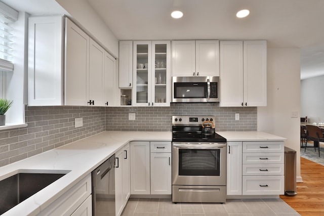 kitchen with appliances with stainless steel finishes, white cabinetry, and light stone countertops