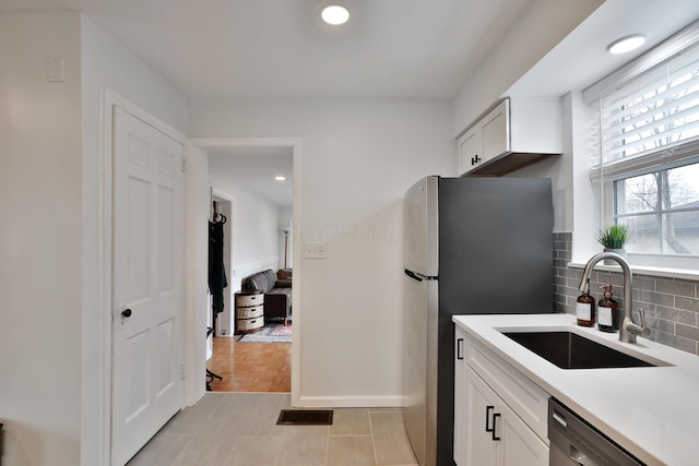 kitchen featuring decorative backsplash, appliances with stainless steel finishes, light countertops, white cabinetry, and a sink