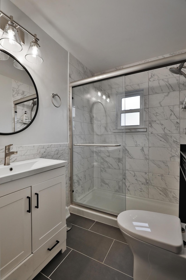 bathroom featuring toilet, a stall shower, tile walls, and vanity