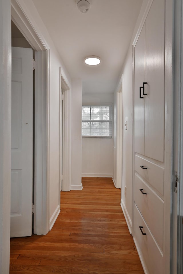 corridor featuring light wood-type flooring and baseboards