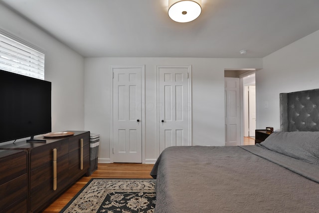 bedroom with multiple closets and wood finished floors