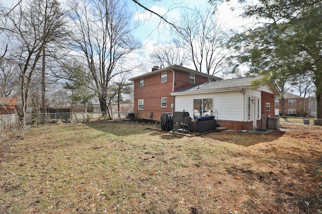 back of property featuring a yard, a chimney, fence, and brick siding