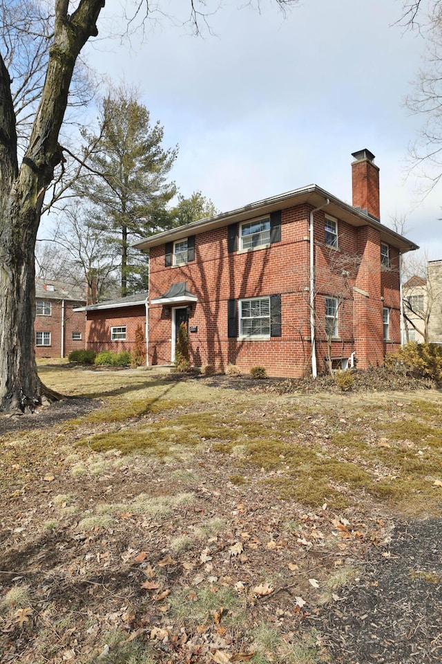 view of front facade featuring a chimney and brick siding