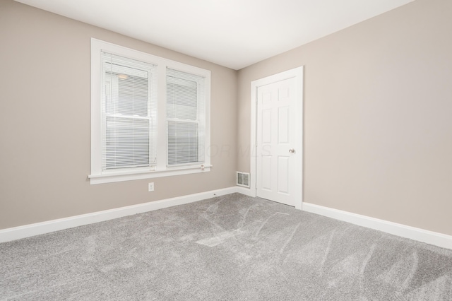 empty room featuring carpet flooring, baseboards, and visible vents