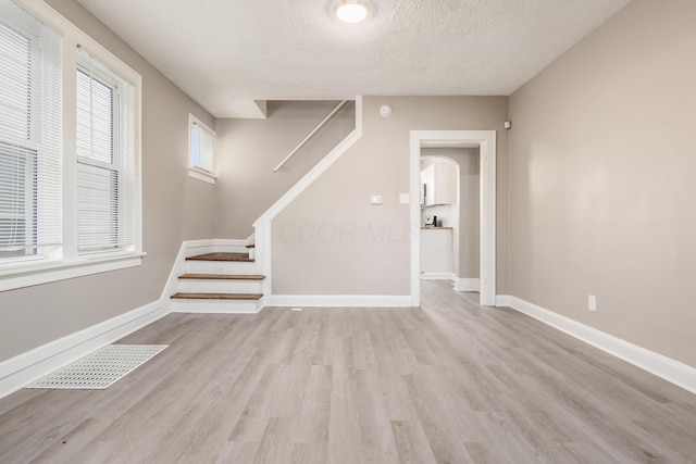 interior space with stairway, wood finished floors, baseboards, visible vents, and a textured ceiling