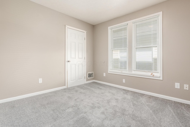 spare room featuring baseboards, visible vents, and carpet floors