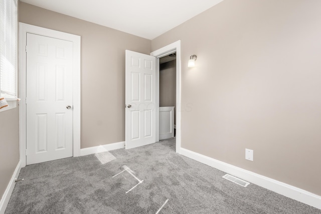 unfurnished bedroom with carpet flooring, visible vents, and baseboards