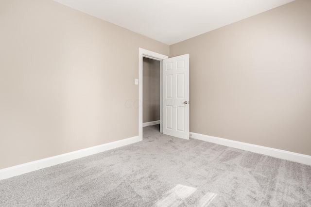 spare room with baseboards and light carpet