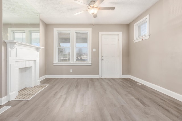 unfurnished living room with a fireplace, baseboards, and light wood finished floors