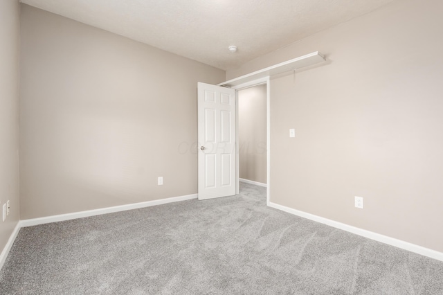 empty room featuring attic access, carpet, and baseboards