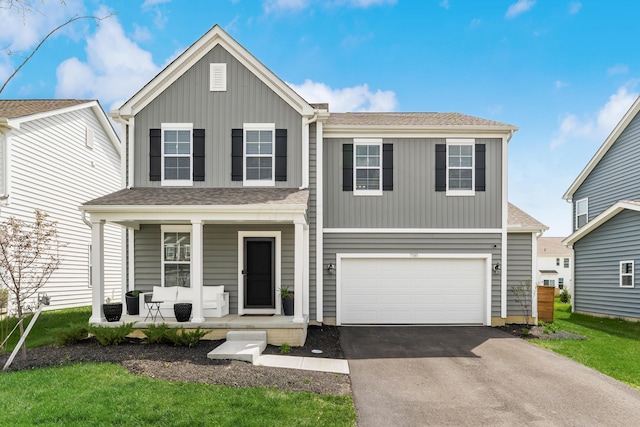 traditional-style house featuring a porch, board and batten siding, an attached garage, and aphalt driveway