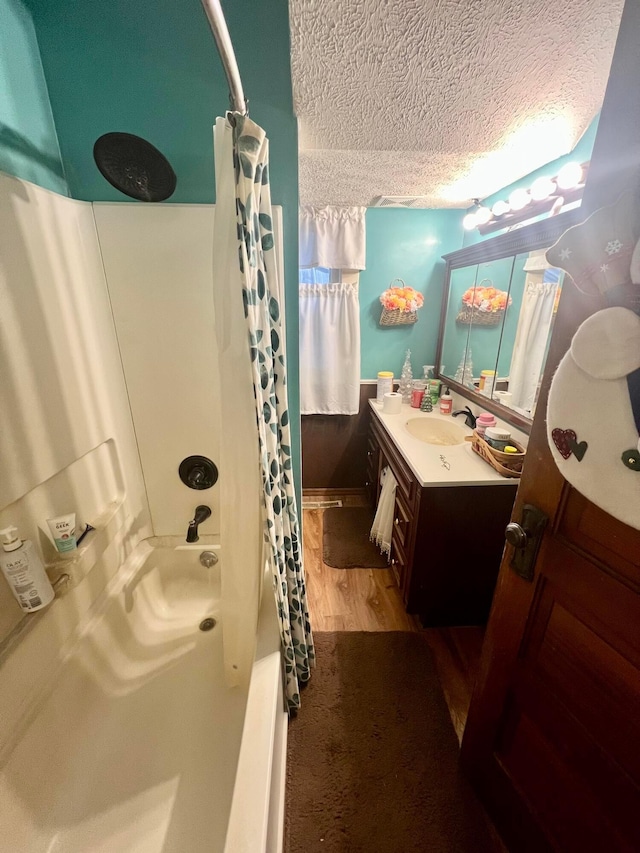 bathroom featuring shower / bath combination with curtain, vanity, a textured ceiling, and wood finished floors