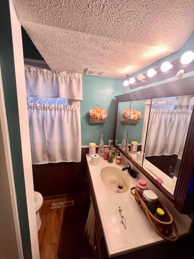 bathroom with visible vents, toilet, wood finished floors, a textured ceiling, and vanity