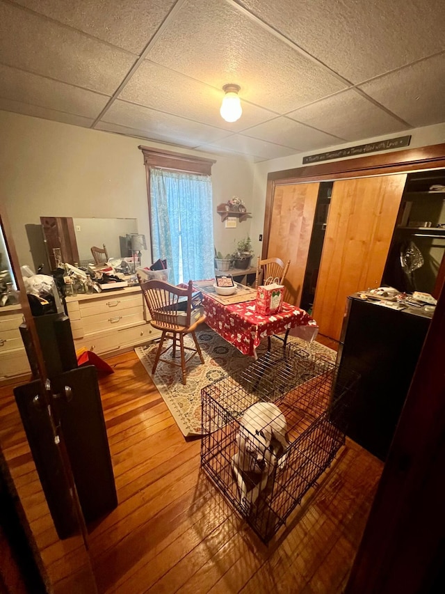 dining room featuring hardwood / wood-style floors and a drop ceiling