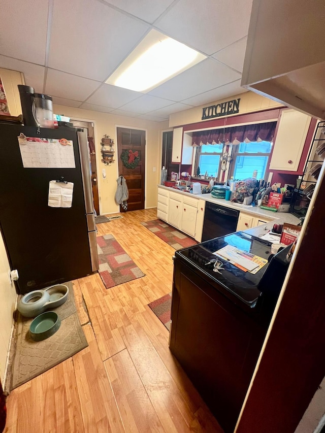 kitchen with light countertops, light wood-style floors, freestanding refrigerator, white cabinetry, and dishwasher