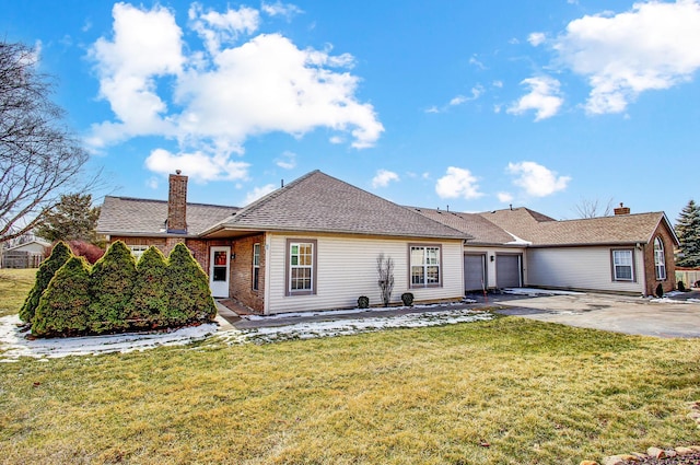 single story home with a garage, driveway, a chimney, a front yard, and brick siding