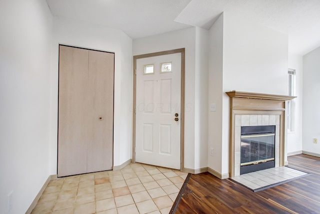 entrance foyer featuring light wood-style floors, a tile fireplace, and baseboards