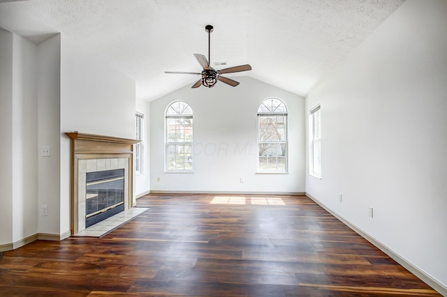 unfurnished living room with lofted ceiling, dark wood-type flooring, a ceiling fan, a textured ceiling, and a tile fireplace